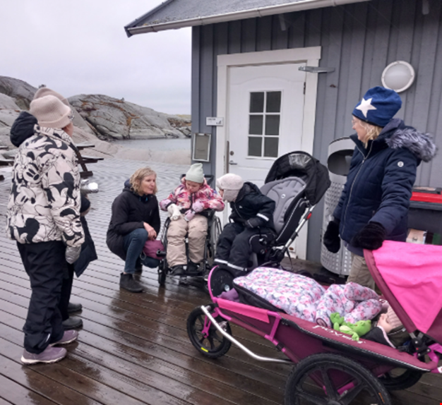 Barn och vuxna i regnet på bryggan