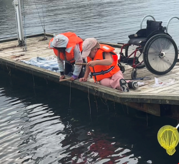 Två barn fiskar krabbor på bryggan.