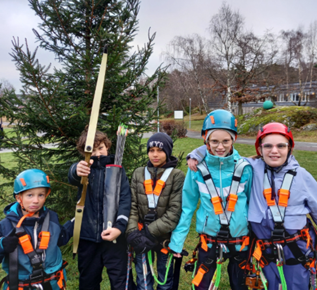 Fem barn poserar framför julgranen redo för zipline.