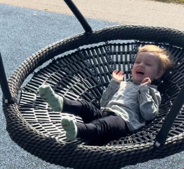 Pojke som ligger i en gunga och skrattar.