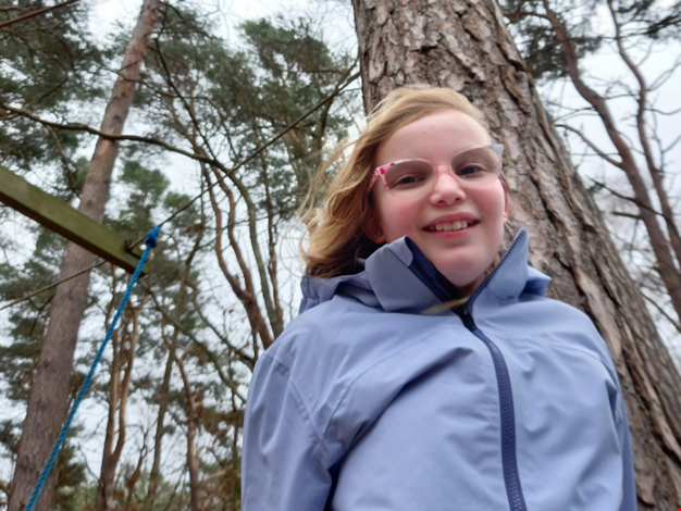 Flicka med glasögon i skogen.