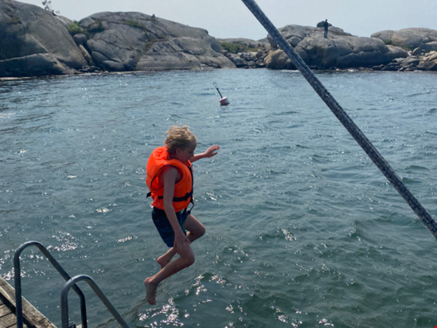 Pojke hoppar från bryggan i vattnet.