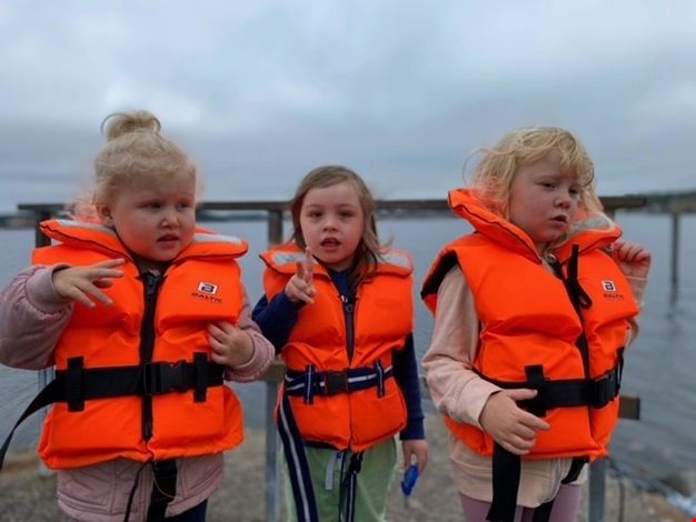 Tre barn i flytväst på bryggan.