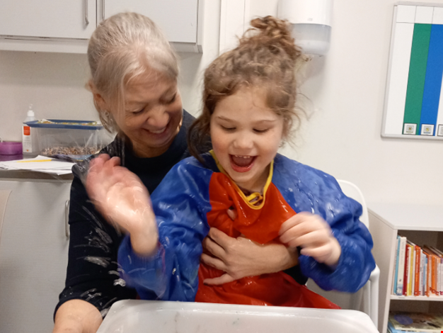 En vxuen och två barn leker med ett fiskspel.