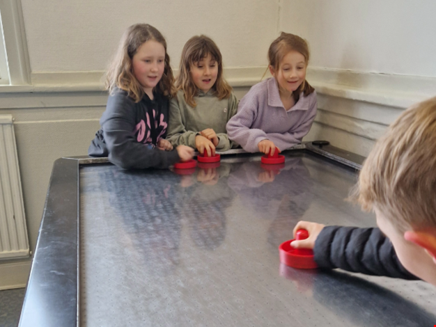 Fyra barn spelar airhockeyspel.