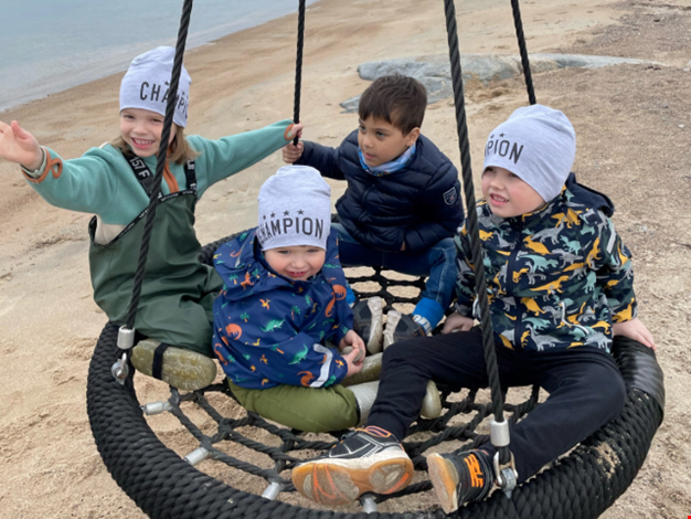 Flera barn gungar i kompisgunga. 