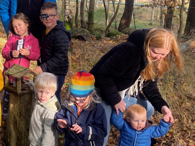 En grupp barn och vuxna på utflykt i skogen. 