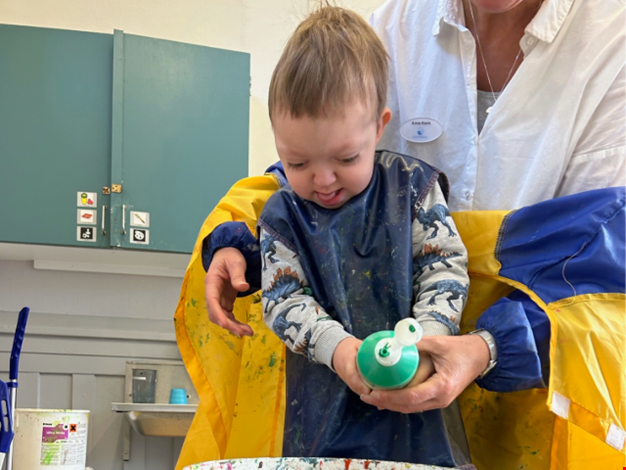 Barn som häller färg i en målarbunke.