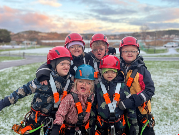 Glada barn i sele poserar redo för zipline.