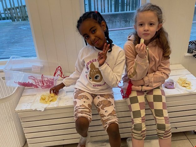 Två tjejer badar fotbad och äter chips.