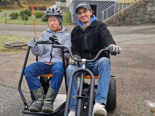 En pojke med personal cyklar trampbil.