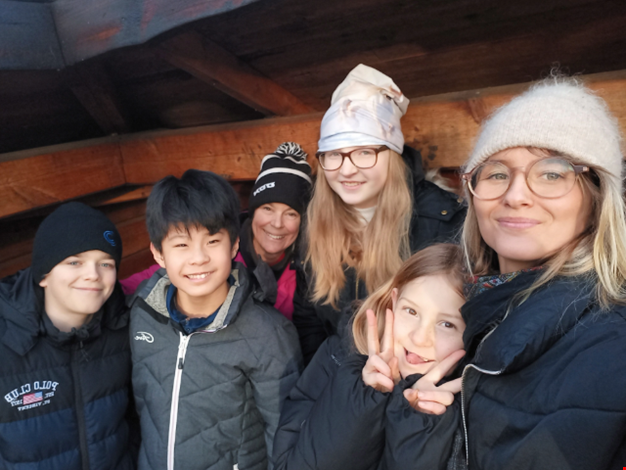 Ett glatt gäng vuxna och barn i solen vid vindskyddet.