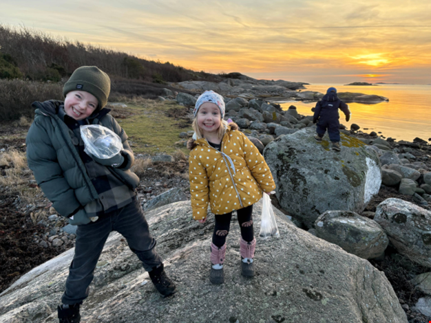 Två barn poserar i solnedgången vid havet. 