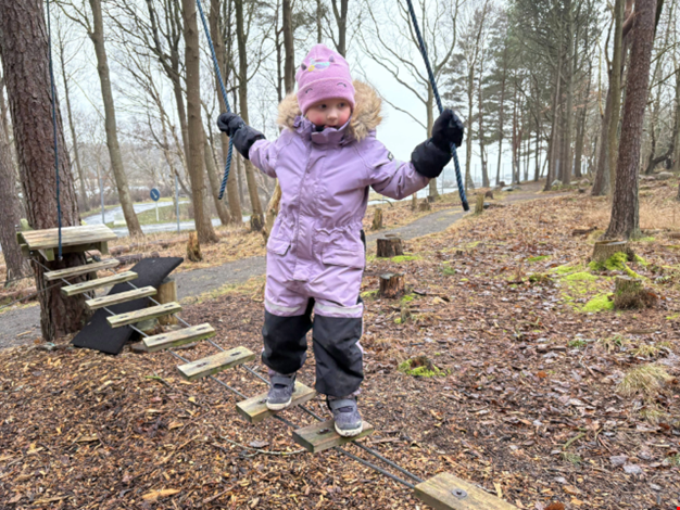 Flicka balanserar på låghöjdsbana i skogen.