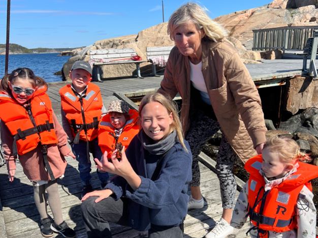 Barn och vuxna visar upp sina nyfiskade krabbor på en brygga. 