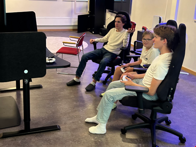 Sigge och två komisar sitter i stolar framför en dator.