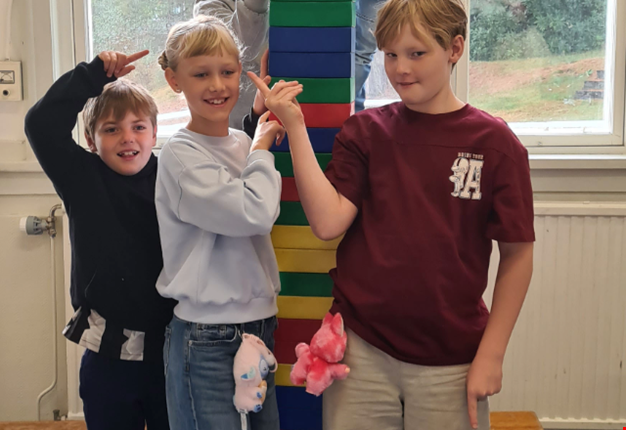 Tre barn har byggt ett torn och visar upp det.
