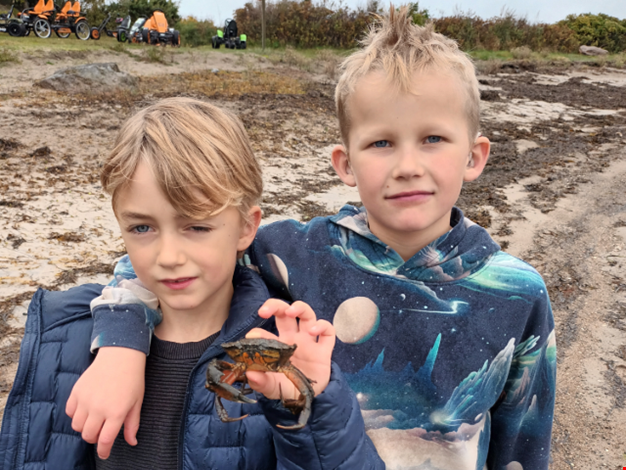 Två pojkar visar upp en krabba de fångat. 