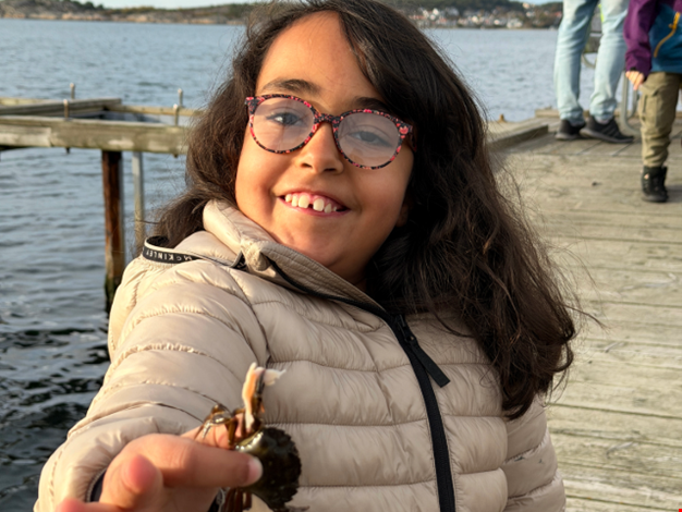 Flicka visar stolt upp sin fångade krabba för kameran.