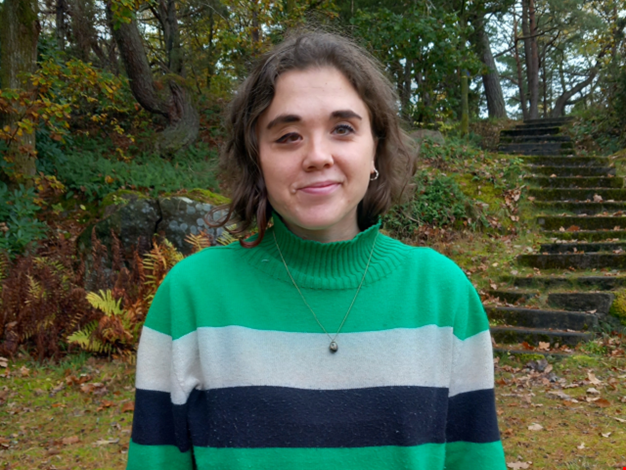 Estelle står framför en trappa som leder upp i skogen. 