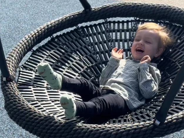 Pojke som ligger i en gunga och skrattar.