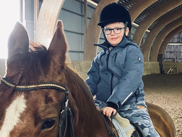 Pojke som rider på en häst.