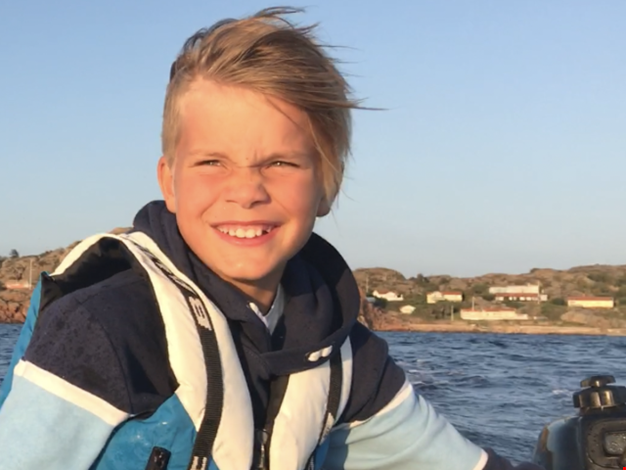 Pojke som styr en motorbåt på havet.