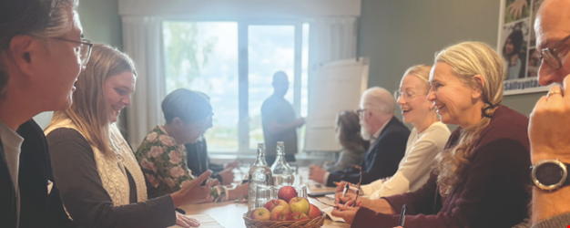 Konferensgäster som sitter runt ett bord i mötesrum.