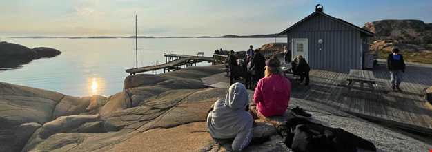 Deltagare i korttidsverksamheten som sitter på klipporna nere vid bastun.